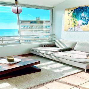uma sala de estar com um sofá e uma grande janela em Charmant T3 vue mer, moderne et tout équipé em Valras-Plage