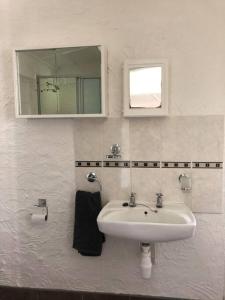 Baño blanco con lavabo y espejo en Roberto's, en Hilton