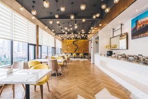 a restaurant with white tables and yellow chairs at Atour Hotel Shanghai Lujiazui Minsheng Road Station in Shanghai