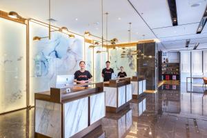 three men standing at a counter in a lobby at Atour Hotel Shenzhen Shajing International Convention and Exhibition Center in Bao'an