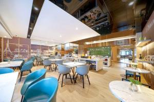 a restaurant with white tables and blue chairs at Atour X Hotel Harbin West Railway Station in Harbin