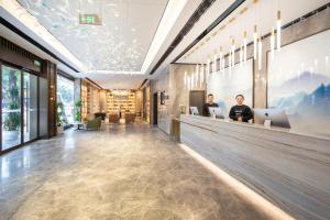 zwei Männer sitzen an einem Tresen in einer Lobby mit ihren Laptops in der Unterkunft Atour Hotel Chongqing Jiangbei International Airport Huixing Light Rail Station in Chongqing