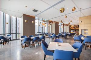un restaurante con sillas azules, mesas y ventanas en Atour S Shenzhen Nanshan en Shenzhen