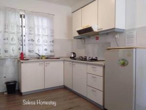 a kitchen with white cabinets and a refrigerator at THAT SPACE@SELESA HILLHOMES, BUKIT TINGGI BENTONG in Bentong