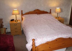 a bedroom with a wooden bed with two lamps on tables at Ullathorns Farm in Kirkby Lonsdale