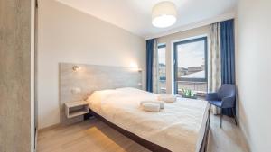 a bedroom with a bed and a chair and a window at Apartamenty Sun & Snow Bank Polski in Gdynia