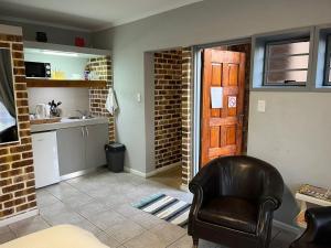 a living room with a chair and a kitchen at The Haven in Nelspruit