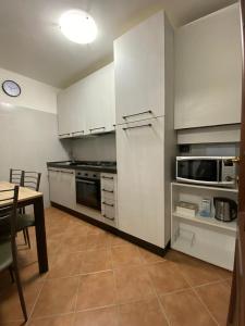 cocina con armarios blancos, mesa y fogones en LAKE HOUSE near Bellagio, en Lezzeno