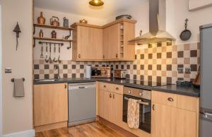 eine Küche mit Holzschränken und einem Herd mit Backofen in der Unterkunft Cornish Tin Mine Themed Apartment in St Austell