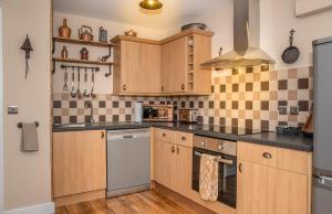 una cucina con mobili in legno e un forno a piano cottura di Cornish Tin Mine Themed Apartment a St Austell