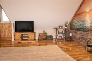 ein Wohnzimmer mit einem Flachbild-TV auf einem Holzboden in der Unterkunft Cornish Tin Mine Themed Apartment in St Austell
