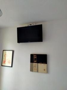 telewizor z płaskim ekranem wiszący na białej ścianie w obiekcie Hotel du Centre w mieście Châlus