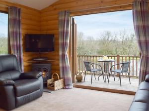 a living room with a balcony with a tv and a table and chairs at Herons Log Cabin in Rosebush