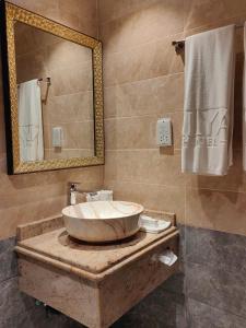ALYA Hotel في بركاء: حمام مع حوض كبير ومرآة