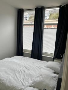 1 dormitorio con 1 cama y 2 ventanas en Poelgeeststraat en Leiden