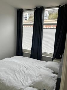 een slaapkamer met een bed en 2 ramen bij Poelgeeststraat in Leiden