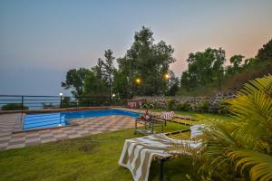 a swimming pool in a yard with a table and benches at Infinity Pool 2bhk Villa with valley view in Panchgani