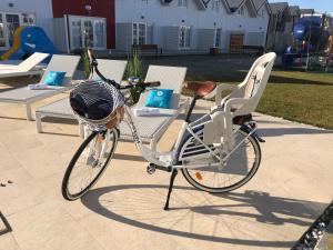 Una bicicleta con una cesta estacionada junto a las sillas en Zatoka Slonca - Domki z basenem, WiFi i parking w cenie! en Mielno