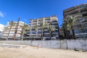 a tall building with palm trees in front of it at DIFFERENTFLATS Barcino in Salou