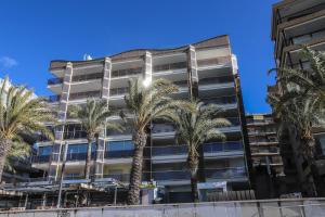 a tall building with palm trees in front of it at DIFFERENTFLATS Barcino in Salou