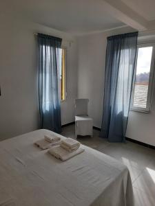 Un dormitorio con una cama blanca con cortinas azules y una silla en Cà gialla de Drignana, en Vernazza