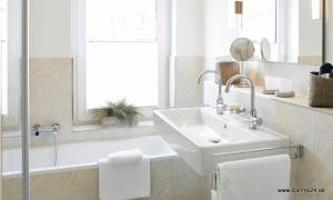 ein weißes Badezimmer mit Waschbecken und Badewanne in der Unterkunft 1904 - Am Kurpark in Dahme