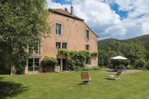 two chairs and an umbrella in front of a building at Domaine de Marmonfosse in Taintrux