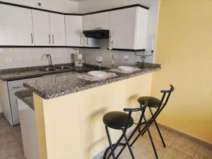 a kitchen with two bar stools and a counter top at sol y mar in Puerto de Santiago