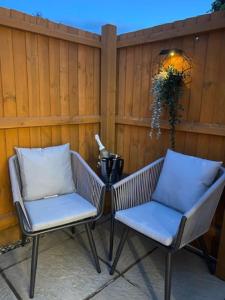 two chairs and a table in front of a fence at Stylish 1 bedroom studio outdoor area and hot tub in Bournemouth