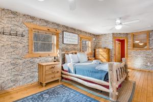 1 dormitorio con cama y pared de piedra en The Birdie Lodge, en Arkdale