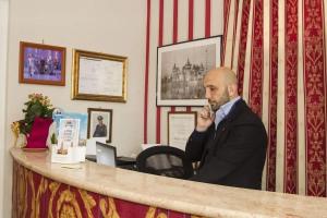 a man sitting at a desk talking on a cell phone at Hotel magnolia 1000 mt dal casello in Valmontone