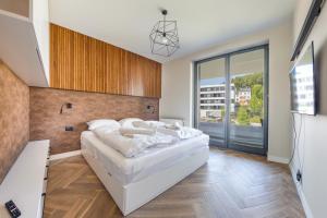a bedroom with a large white bed and a large window at Apartamenty Sun & Snow Silva in Gdynia