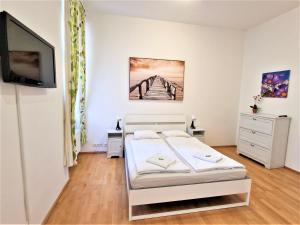 een witte slaapkamer met een bed en een televisie bij Reznicka Apartments in Praag