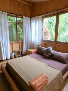 una camera con un grande letto in una stanza con finestre di Monsoon Eco Resort - Whisky point Arugambay a Pottuvil