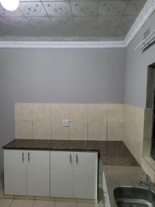 a kitchen with white cabinets and a sink at Mavundla lifestyle lodge in Empangeni