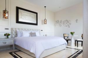 a white bedroom with a white bed and a table at Más Palomas Concept House by Paloma's Hotels - Adults Only in Mérida