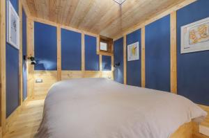 a bedroom with blue walls and a large white bed at Petit Bleu in Chamois