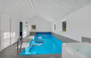 een kamer met een blauw zwembad met een bad bij Amazing Home In Oksbl With Indoor Swimming Pool in Oksbøl