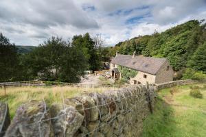 Ein altes Haus auf einem Feld neben einem Zaun in der Unterkunft Twitchill Farm Holiday Cottage in Hope