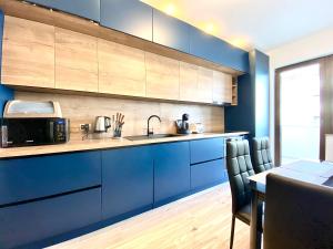 une cuisine avec des placards bleus et une table avec des chaises dans l'établissement Coquette Apartment, à Braşov