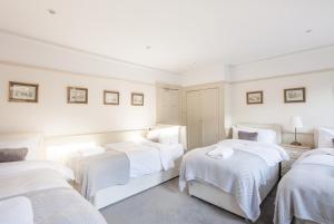 a white room with three beds with white sheets at City Centre Stunning House-Roman Baths - 3min walk - 4 Bedrooms in Bath