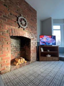 a brick fireplace with a tv in a room at The Boathouse - Hottub - Sleeps 6 in Woodhorn