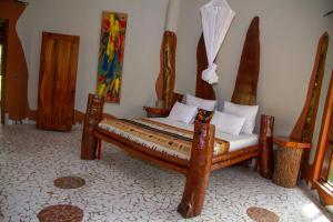 a bedroom with a wooden bed in a room at Mama Africa Art Residence & Art Center Gambia in Tanji