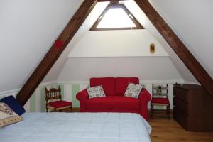 a bedroom with a red couch in a attic at Villa Molteni, Ville di Fiemme, Varena in Varena