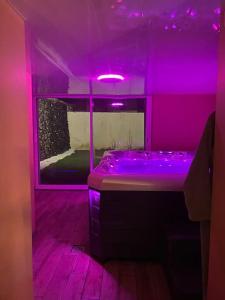 a purple bathroom with a tub with a purple lighting at BEAUTIFUL LIFE BED and SPA in Mirecourt