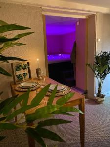 ein Wohnzimmer mit einem Tisch und einem lila Licht in der Unterkunft BEAUTIFUL LIFE BED and SPA in Mirecourt