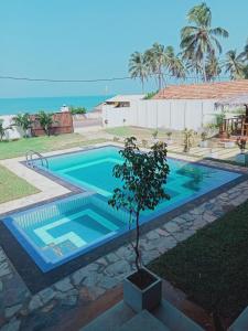 ein Schwimmbad mit einem Baum in der Mitte in der Unterkunft ISAMAR FRONT BEACH in Marawila