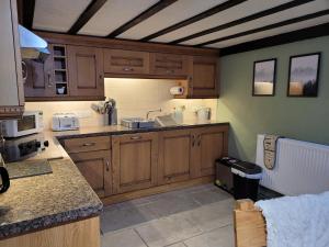 a kitchen with wooden cabinets and a counter top at The Granary Corris on the edge of the Dyfi Forest in Corris