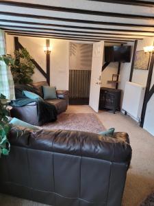 a living room with a leather couch and a television at The Granary Corris on the edge of the Dyfi Forest in Corris