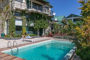 a woman sitting on a chair next to a swimming pool at Villa Mountain Crest Kasauli with Treehouse & Sundeck in Dagshai